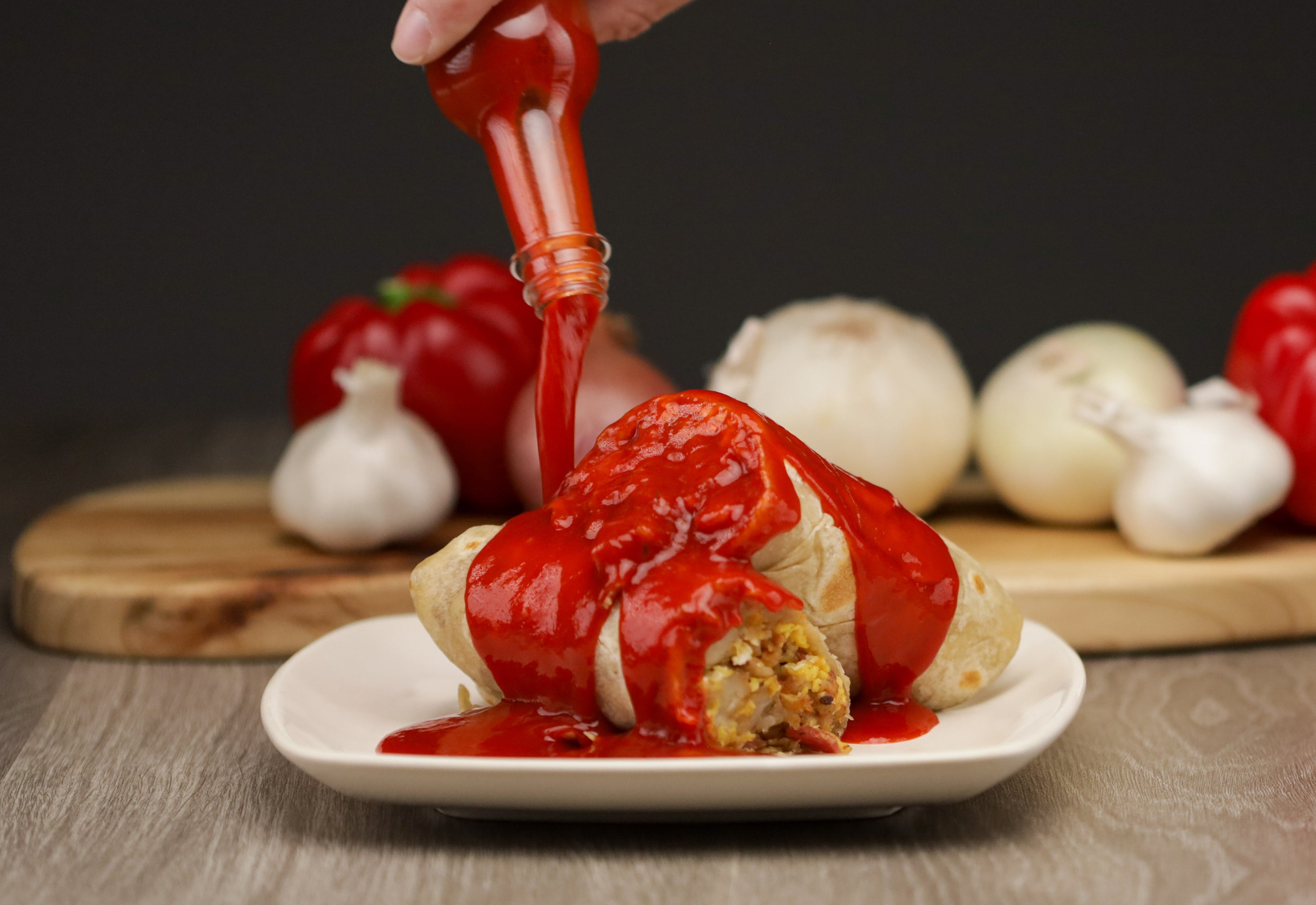 photo of a bottle of Ghost sauce being poured onto a breakfast burrito