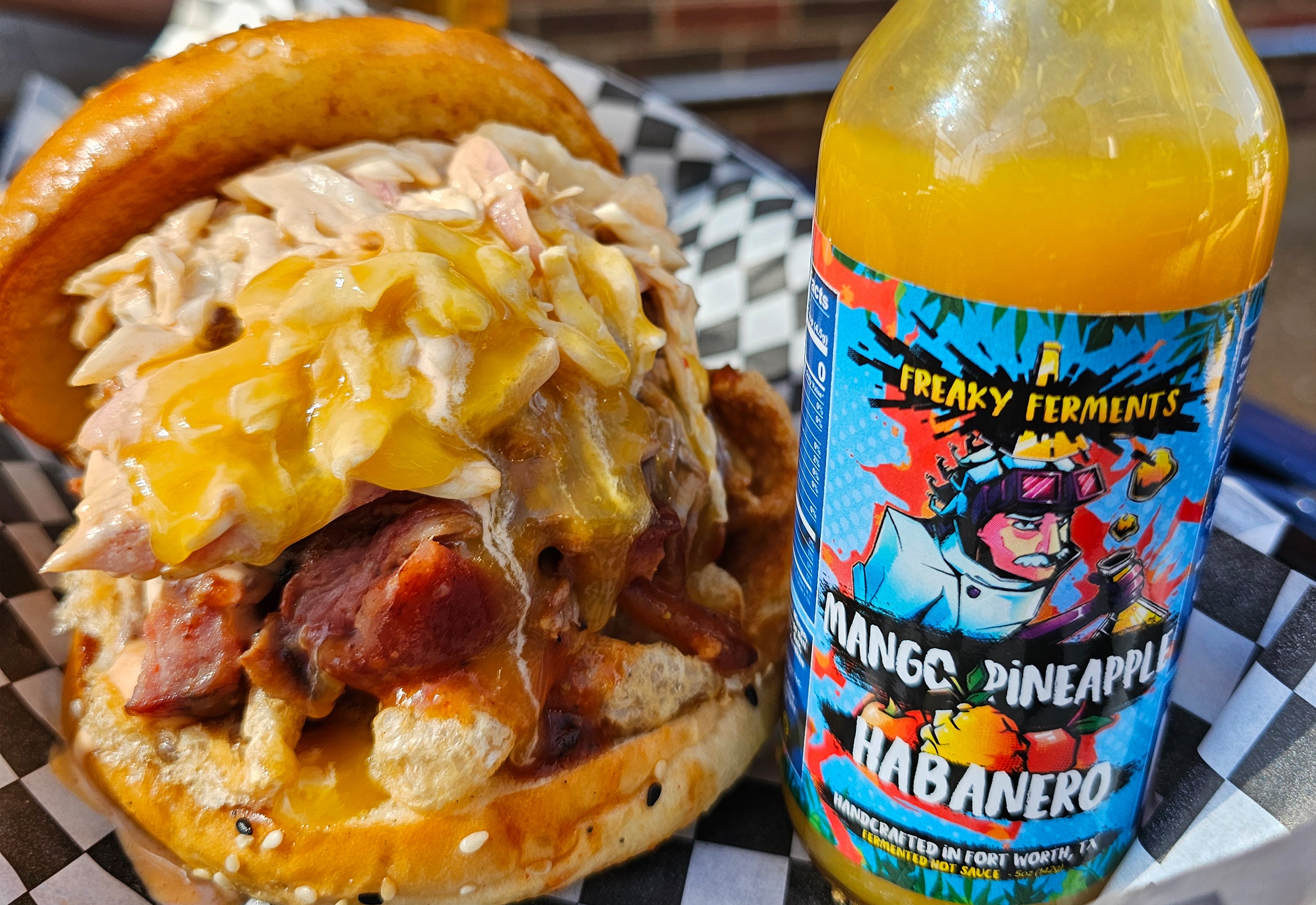 photo of a bottle of Mango Pineapple Habanero next ot a pork sandwich