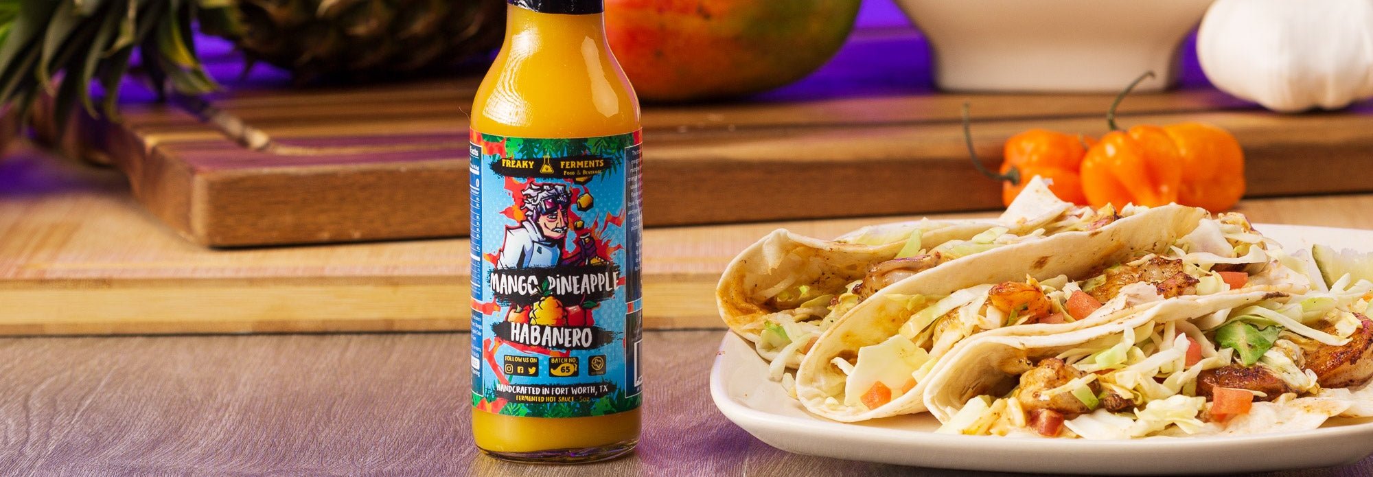 photo of mango pineapple habanero bottle next to fish tacos